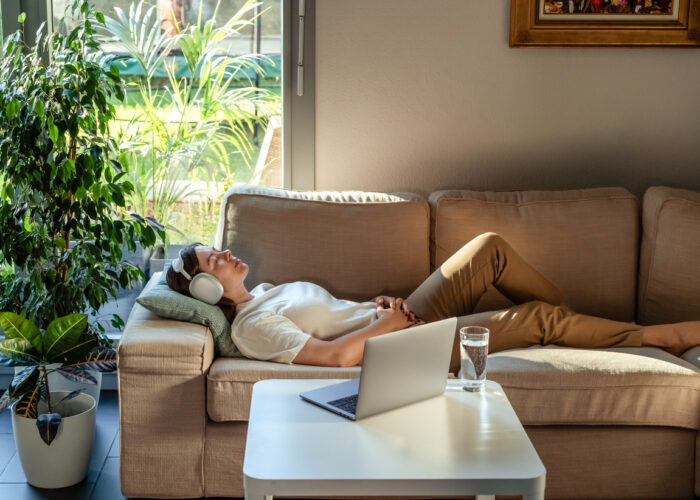 Young woman having online hypnotherapy regression session with psychotherapist lying on sofa at home. Digital service